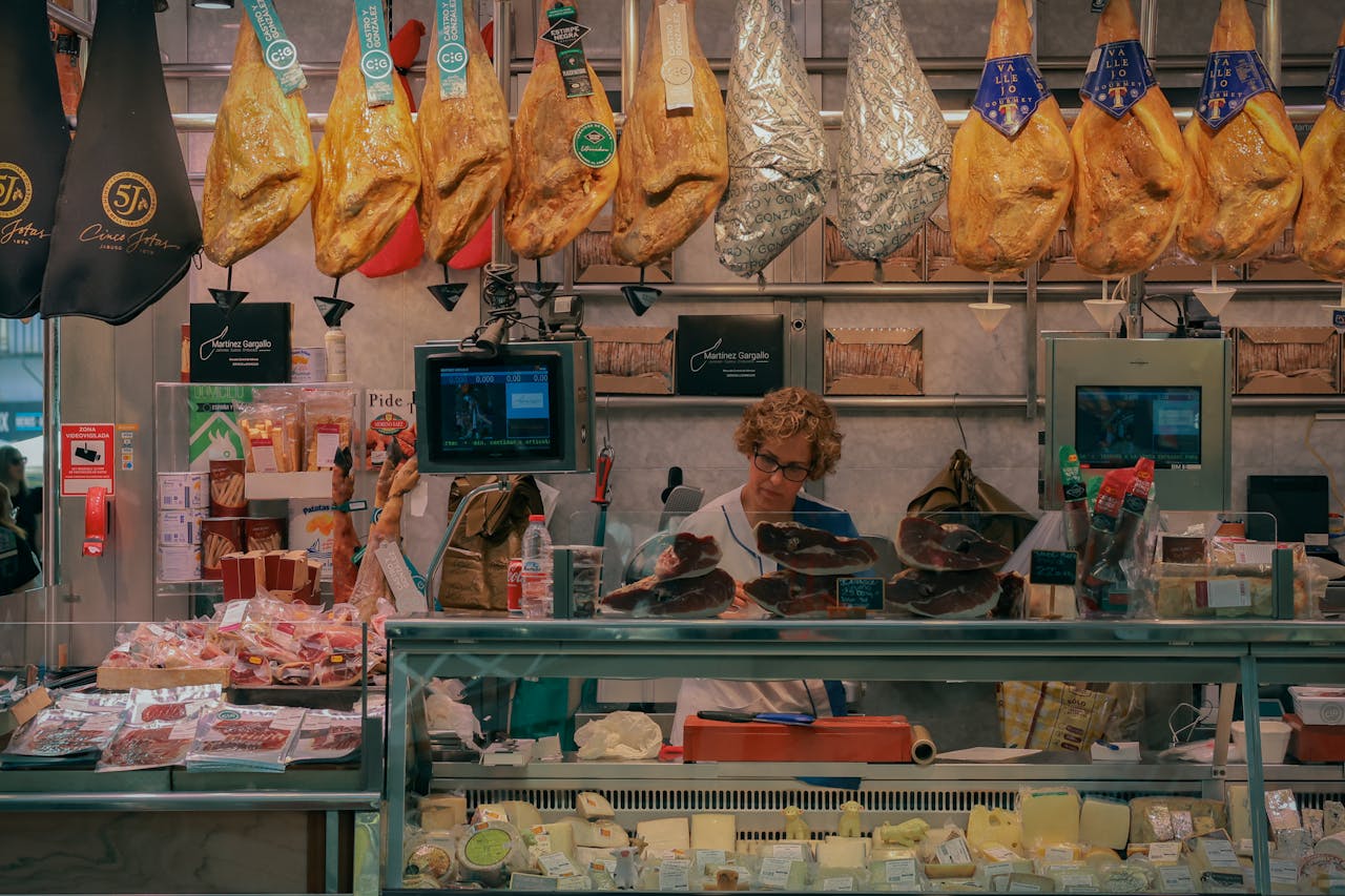 A bustling market stall in Valencia, Spain, showcasing jamón and various cheeses.