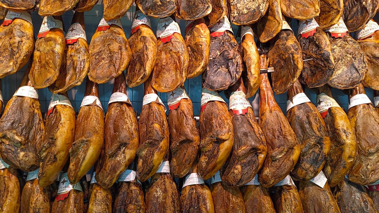 Captivating display of traditional Jamón Ibérico hanging in a vibrant Spanish market.
